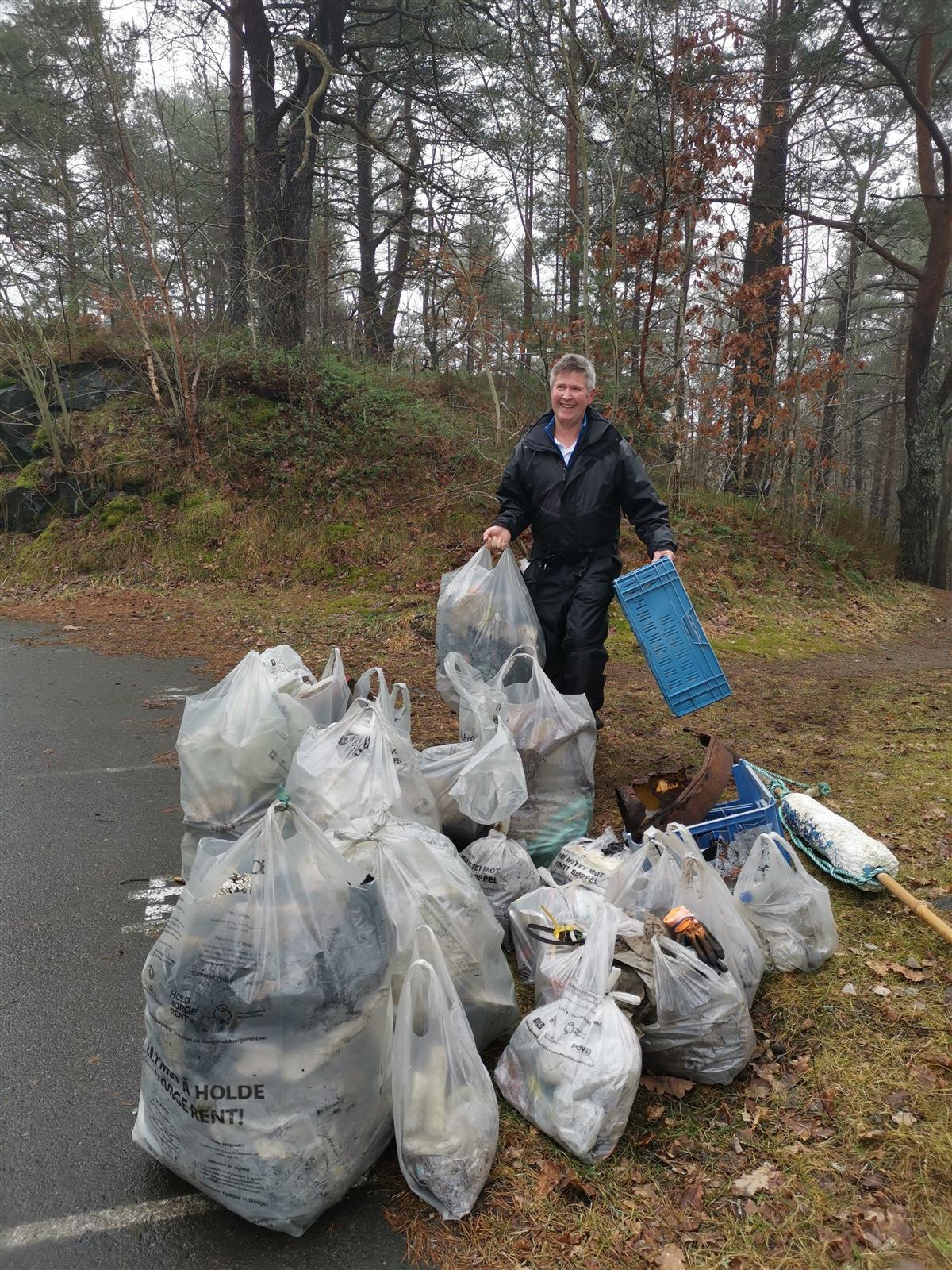 En mann står sammen med en haug med søppelposer - Klikk for stort bilde